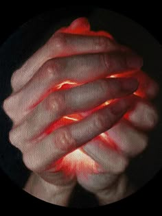 a person holding their hands together with red light coming from them in front of the camera