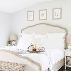 a bedroom with white bedding and pictures on the wall