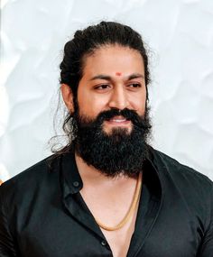 a man with a long beard wearing a black shirt and gold chain around his neck