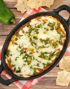 a pizza in a cast iron skillet with cheese and green peppers on the side