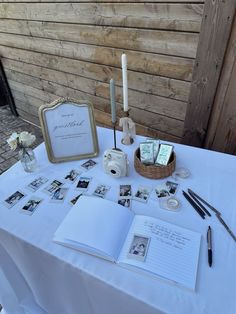 an open book sitting on top of a white table covered in pictures and other items