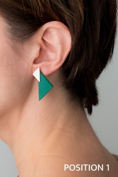 a woman wearing green and white earrings with an arrow on the back of her ear