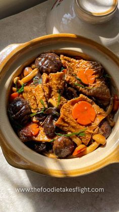 a bowl filled with meat and vegetables next to a cup of coffee