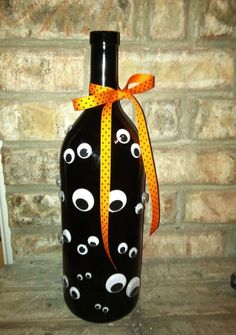 a black bottle with googly eyes on it and a yellow ribbon tied around the neck