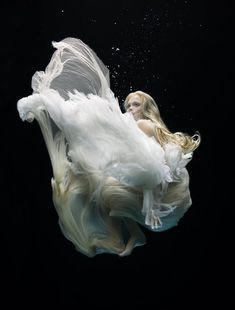 a woman in white dress floating under water