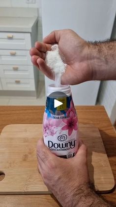 a man holding up a bottle of dough on top of a wooden cutting board