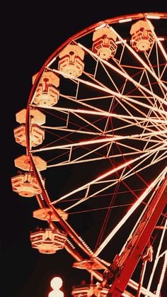 a ferris wheel lit up at night with the lights on and no people around it