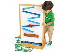 a young boy standing next to a white board with blue pencils on it