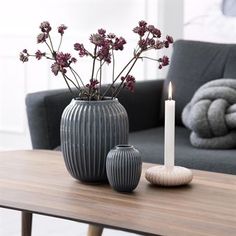 two vases with flowers in them sitting on a table next to a couch and chair