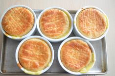 four white bowls filled with food sitting on top of a metal pan