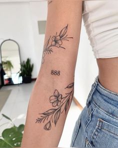 a woman's arm with flowers and the number 868 tattooed on her left arm