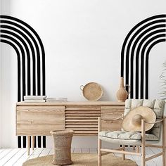 a room with black and white stripes on the wall, a chair, table and vase