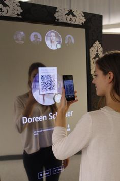 a woman standing in front of a projector screen holding up two cell phone screens