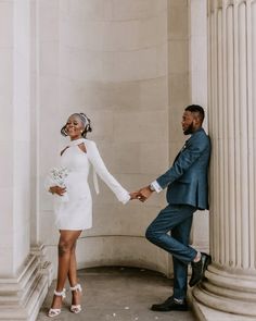 a man and woman holding hands in front of columns