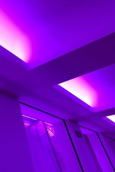 an empty room with purple lighting in the ceiling