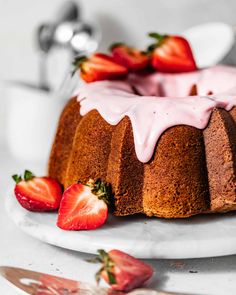 a bundt cake with strawberry icing and sliced strawberries on the plate next to it