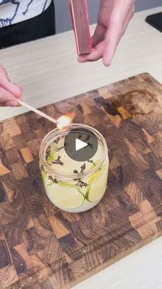 a person lighting a candle on top of a wooden cutting board