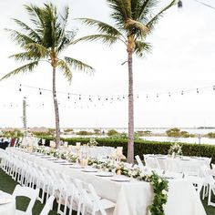 a long table with white linens and greenery is set up for an outdoor wedding reception