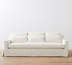 a white couch sitting on top of a hard wood floor next to a white wall