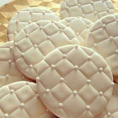 some white cookies sitting on top of a gold platter filled with frosting dots