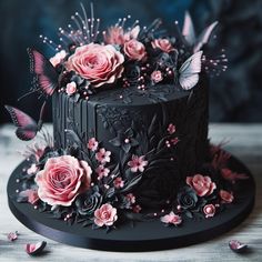 a black cake decorated with pink flowers and butterflies