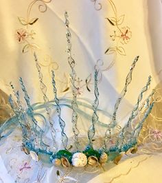 a tiara with beads and pearls on it sitting on a white cloth covered table