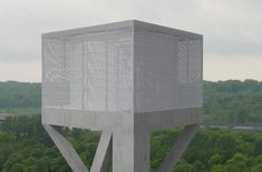 a tall white structure sitting on top of a lush green forest filled with trees next to a highway