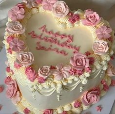 a heart shaped birthday cake with pink roses on it's edges and the words happy birthday written in frosting