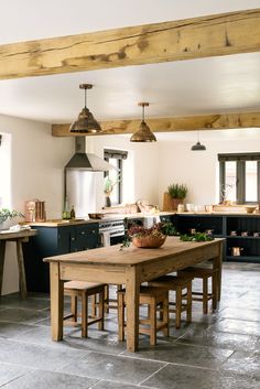 a kitchen with an island table and stools in the center, surrounded by potted plants