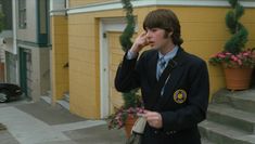 a young man in a school uniform talking on his cell phone