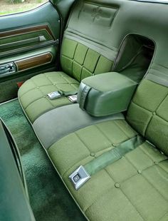 the interior of an old car with green leather and wood trims, including two matching seats