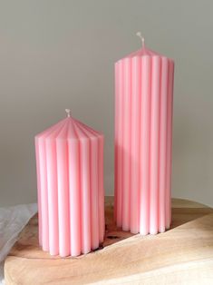 two pink candles sitting on top of a wooden table