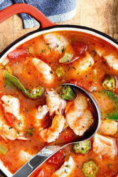 a bowl of chicken and vegetable soup with a spoon in it, on top of a wooden table