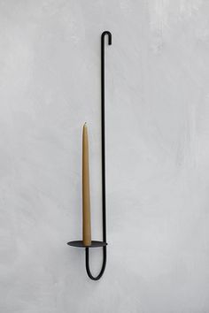 a wall mounted candle holder with a long stick sticking out of it's side