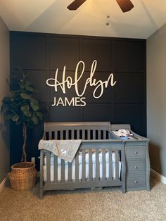 a baby's room with a gray crib and white lettering on the wall