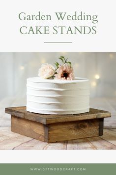 a white cake sitting on top of a wooden stand with flowers in the icing