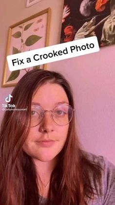 a woman wearing glasses with the words fix a crooked photo above her head, in front of a pink wall