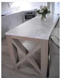 a kitchen island with marble top and wooden legs