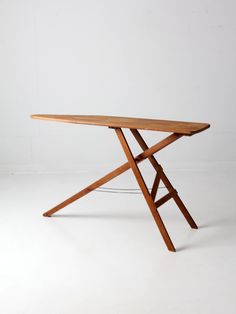 a wooden table sitting on top of a white floor next to a metal object in the shape of an x