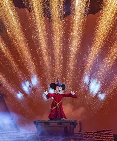 mickey mouse on stage with fireworks in the background