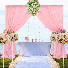 an outdoor ceremony setup with pink drapes and white flowers on the aisle, overlooking the ocean