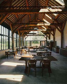 the inside of a building with tables and chairs set up for lunch or dinner in front of large windows