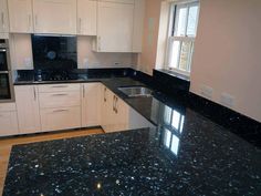 a kitchen with black granite counter tops and white cabinets