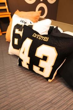 a football jersey pillow on top of a bed with two pillows in front of it