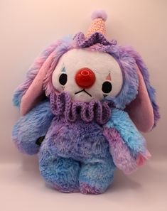 a purple and blue stuffed animal with a clown nose