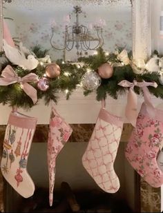 christmas stockings hanging from a mantel decorated with pink and gold ornaments, bows and lights