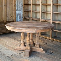 an old wooden table sitting on top of a hard wood floor next to bookshelves