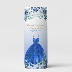 a candle with a blue dress on the front and white flowers around it that reads, celebrate the anniversary of quincaanera