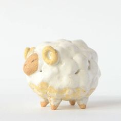 a white and yellow sheep figurine sitting on top of a table