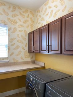 a washer and dryer in a small room with cabinets on either side of the window